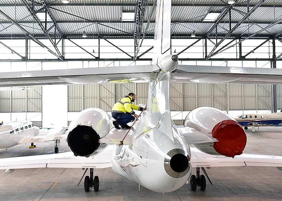 Airport workers check an aircraft for safety in a hangar. — industryviews // Shutterstock