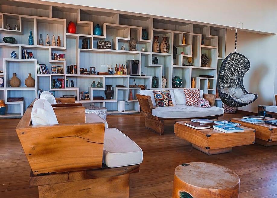 Interior of a luxury modern home's living room showcasing a wide shelf of antiques and books on display. — Pandora Pictures // Shutterstock