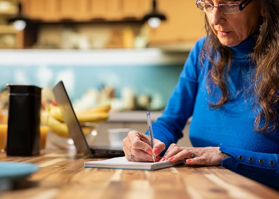 An elderly person writing a grocery list in a kitchen table. — DC Studio // Shutterstock