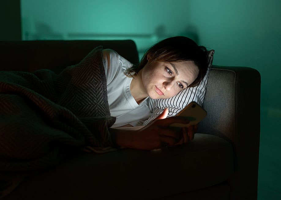 A person surfing internet from her smartphone in a dark room at night. — DimaBerlin // Shutterstock