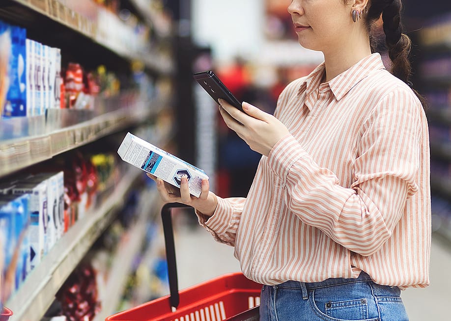 A person scanning a QR code of a product from her smartphone in a supermarket. — STEKLO // Shutterstock