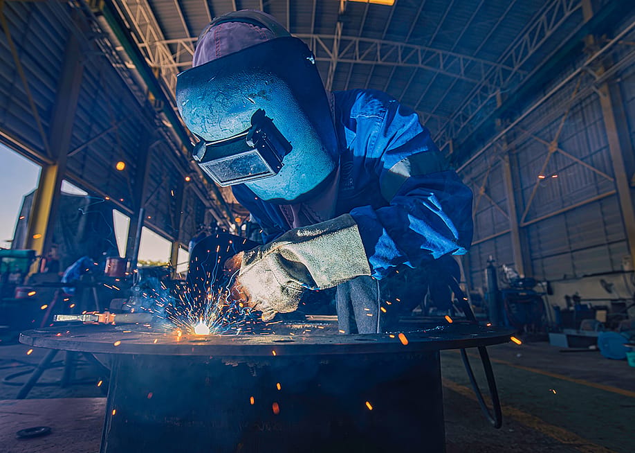 A person doing a mig welding on steels in a warehouse. — noomcpk // Shutterstock