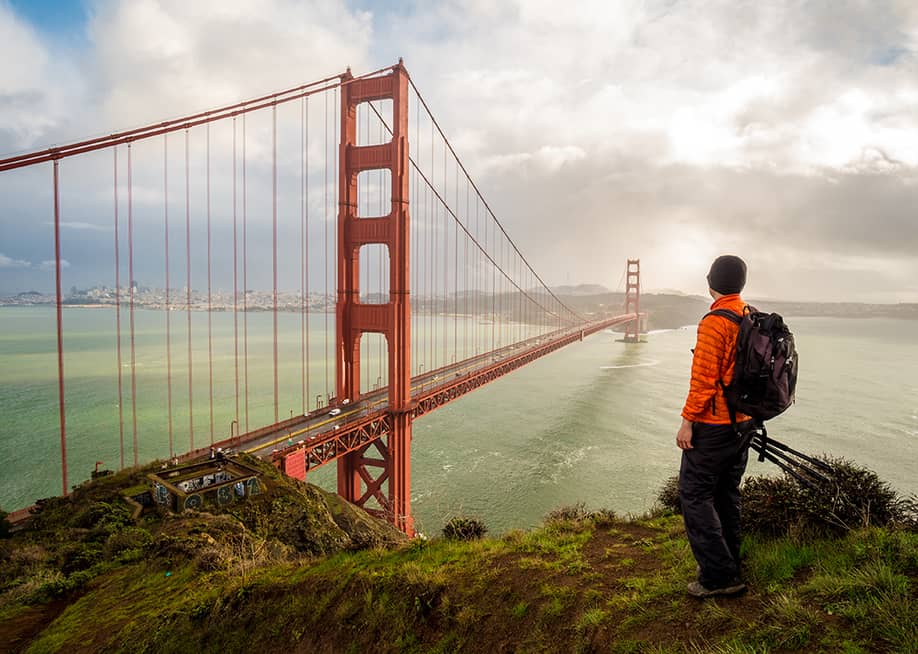 A hiker-traveler looking at the famous Golden Gate Bridge in San Francisco, USA. — Panpilas L // Shutterstock