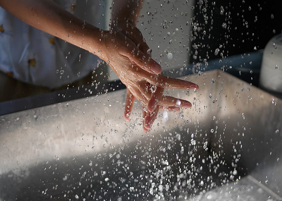 Person washing hands over a sink. — Katekaew Limsanon // Shutterstock