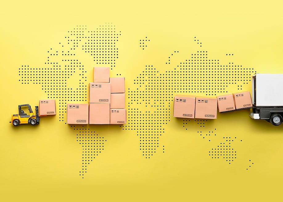 A loader loads goods into a truck against the backdrop of a world map. — ilikeyellow // Shutterstock