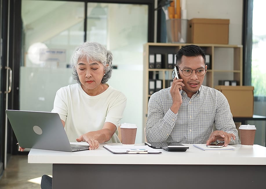 Co-business owners separately talking with customers using different devices. — Kiattisak Th // Shutterstock