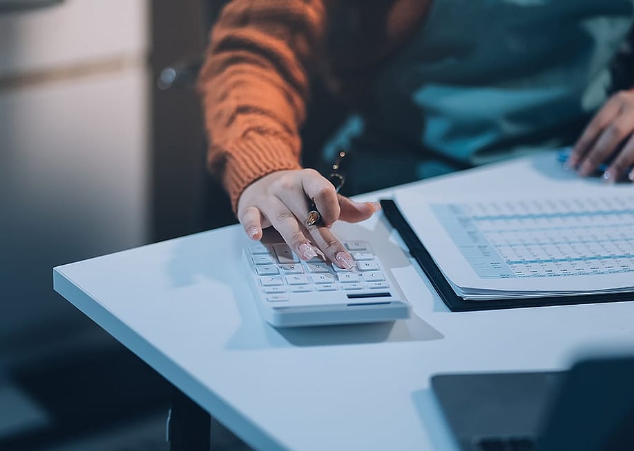 Worker calculating finance reports using a calculator. — ARMMY PICCA // Shutterstock