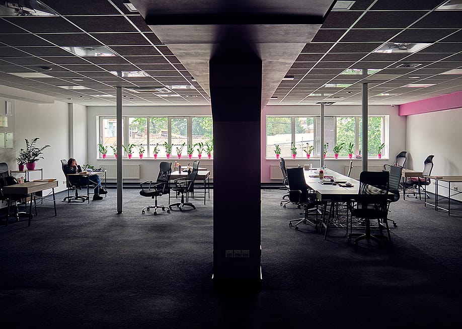 A female employee alone in a big office. — badahos // Shutterstock
