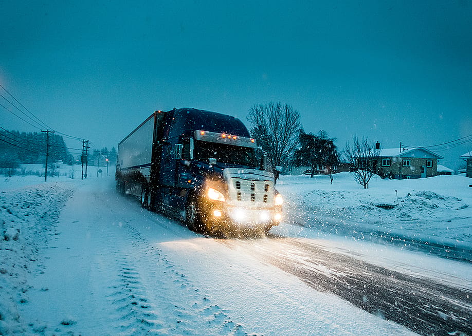 A truck passing on a road during a blizzard in Gaspe, Quebec, Canada. — Benoit Daoust // Shutterstock