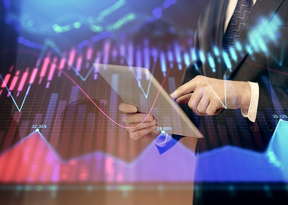A financial marketer using a tablet with an overlay of forex graphs. — Peshkova // Shutterstock