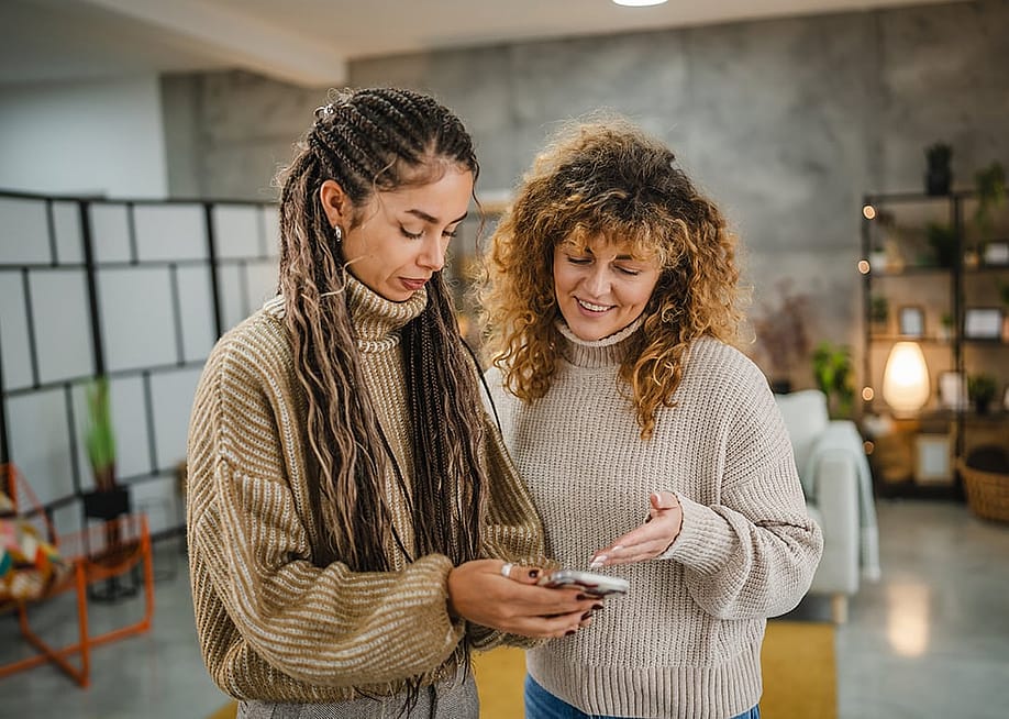 Two friends checking online and making digital payments from a smartphone. — Miljan Zivkovic // Shutterstock