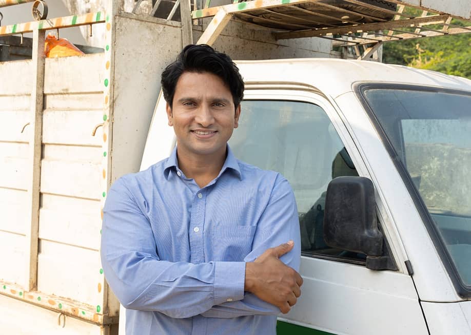 A driver posing for a photo next to a small truck after a delivery. — stockpexel // Shutterstock