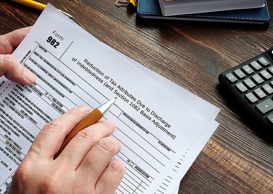 Person reviewing to sign a Form 982. — Yuriy K // Shutterstock