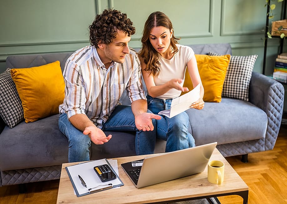 A young couple at home discussing bills. — Mladen Mitrinovic // Shutterstock