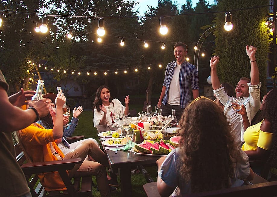 A group of friends laughing together and enjoying their time during a backyard party. — VesnaArt // Shutterstock