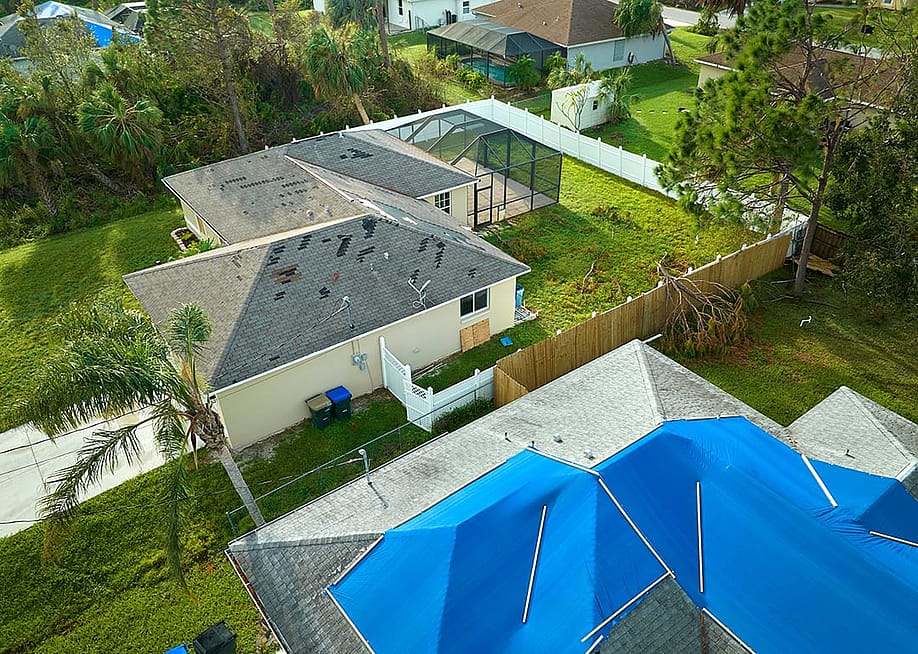 Aerial view of a house's roof damaged by Hurricane Ian in Florida. — Bilanol // Shutterstock