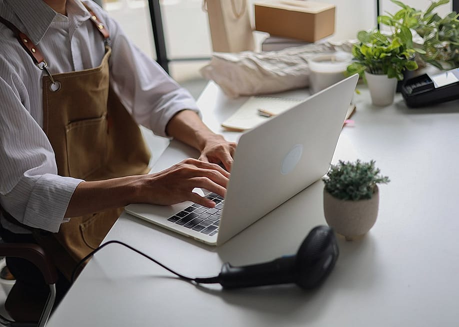 A cafe owner managing online orders from a laptop. — Seacalm // Shutterstock