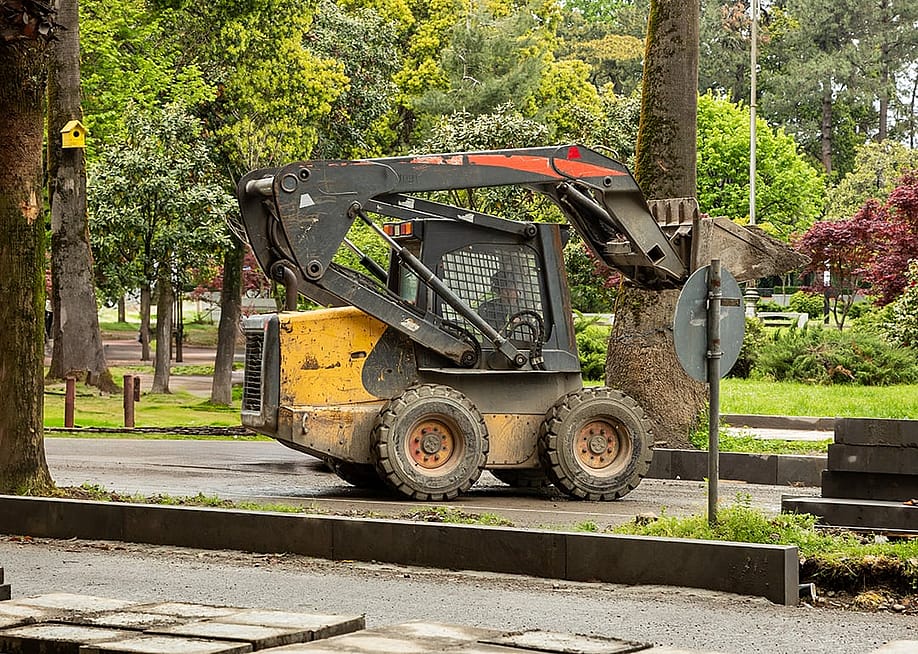 A skid steer loader operating on the park. — TashaAsha // Shutterstock