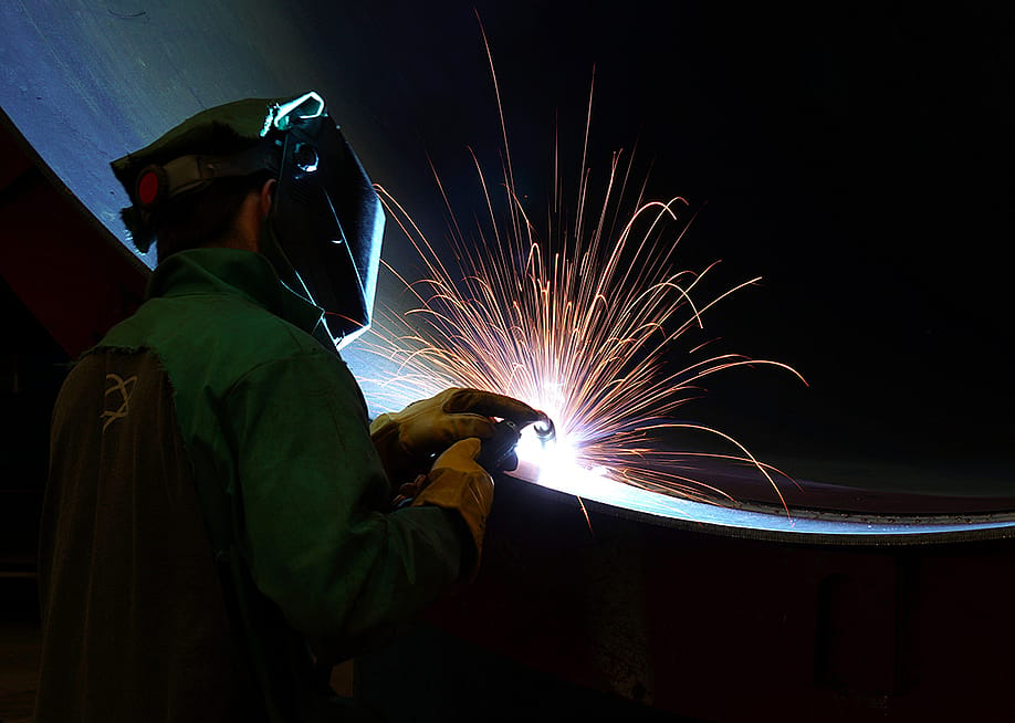 A worker welding a very large steel pipe. — Shelly Short // Shutterstock