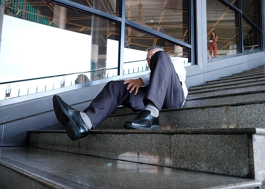 An elderly person getting injured after falling down the stairs in a workplace. — KrongPhoto // Shutterstock