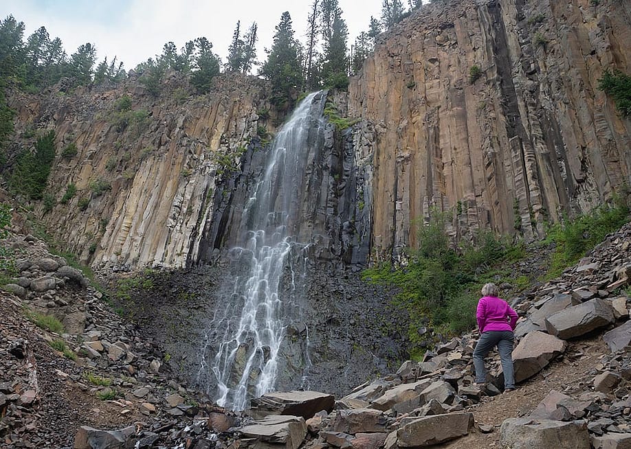 A senior woman at the base of Palisade Falls in Montana. — Teresa Otto // Shutterstock