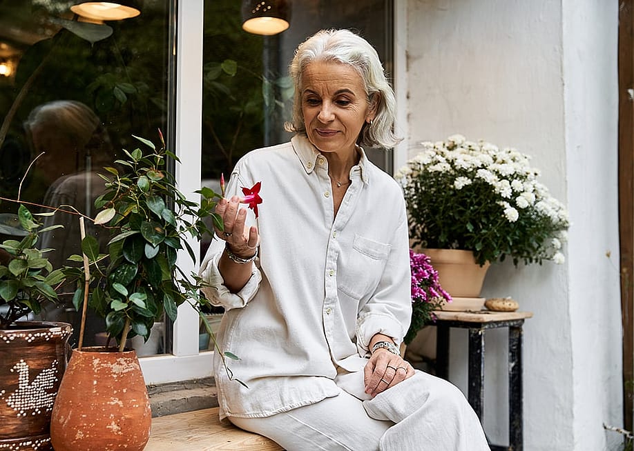 A senior woman sitting in her garden and looking at flowers. — LightField Studios // Shutterstock