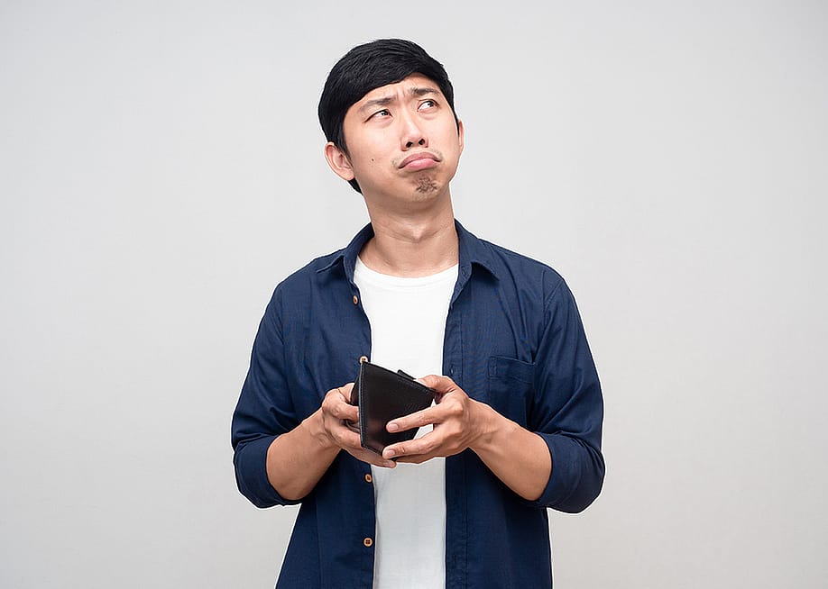 A frugal man confusingly holding an empty wallet. — ToffeePhoto // Shutterstock