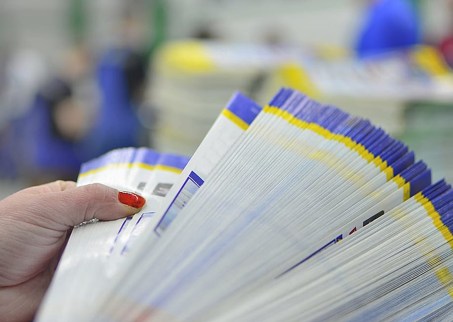 Person checking pages of printed paper. — zefart // Shutterstock
