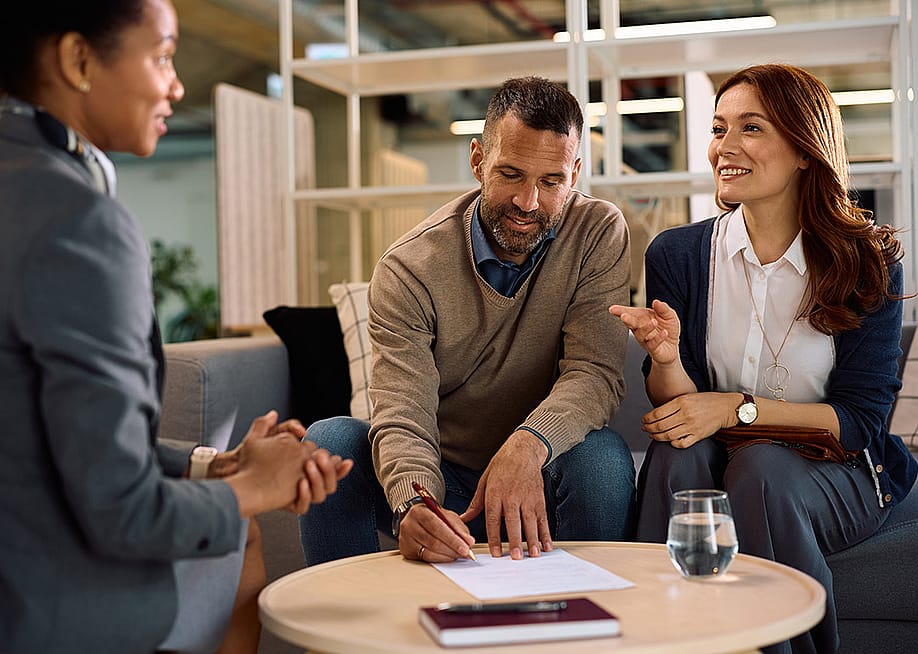 A couple meeting with a financial advisor for an insurance's contract signing. — Drazen Zigic // Shutterstock