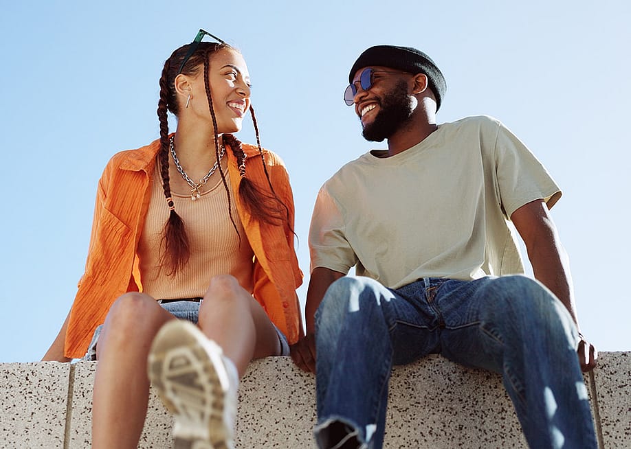 A couple bonding together while enjoying in a sitting wall outdoors. — PeopleImages // Shutterstock