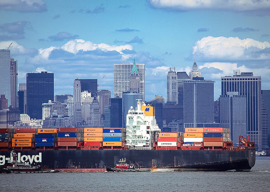 A large container ship carrying imported products entering a port in New York. — MikeDotta // Shutterstock