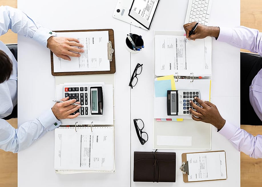 An overhead shot of a tax accountant and an auditor checking on receipts in an office. — Andrey_Popov // Shutterstock