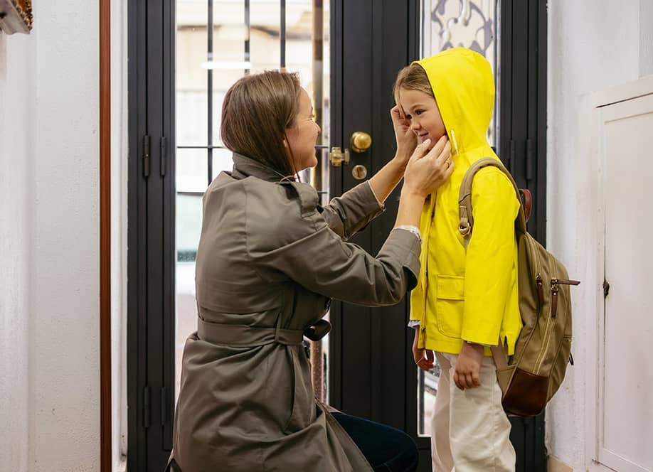 A mother preparing her child to go to school with a raincoat. — alvan.ph // Shutterstock