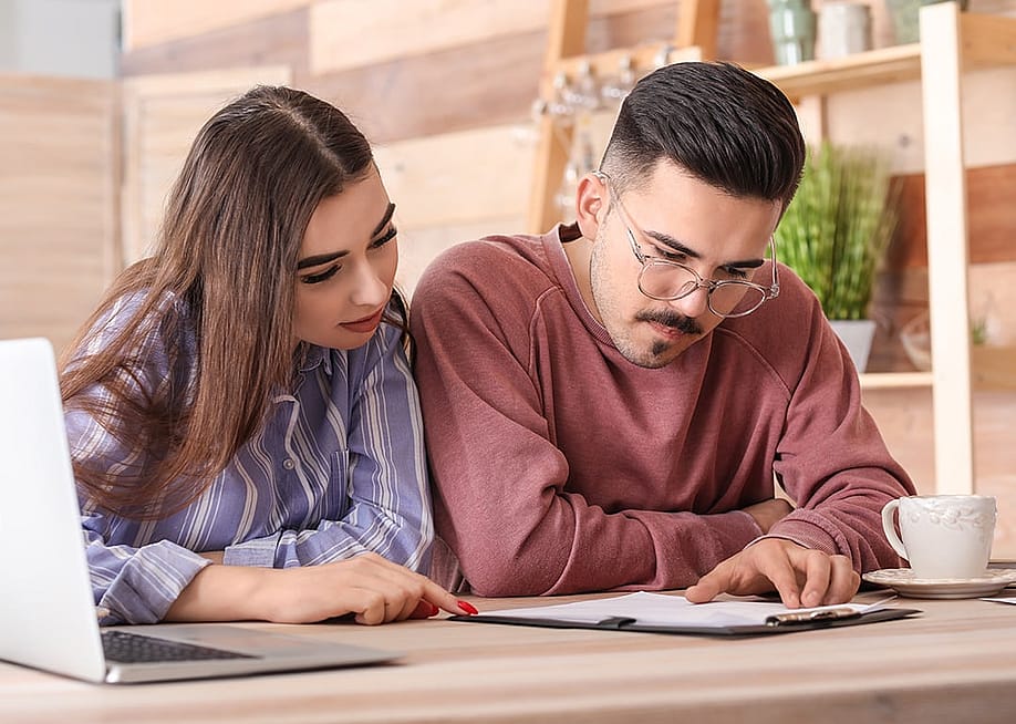 A young couple reviewing an insurance contract in a cafe. — Aquarius Studio // Shutterstock