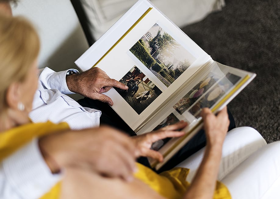 An elderly couple browsing and looking through a photo album. — Rawpixel.com // Shutterstock