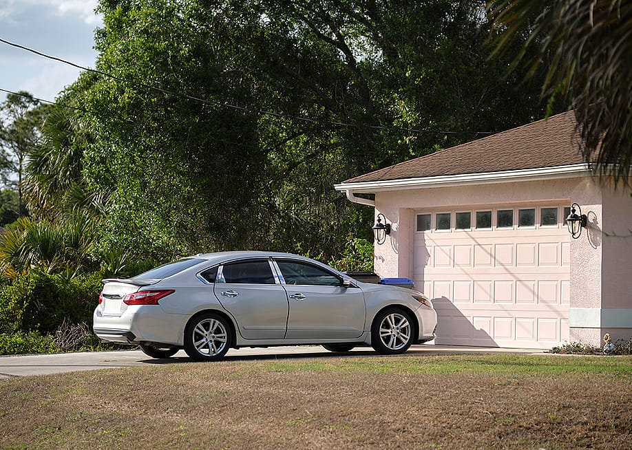 A car parked in front of a modern American house's garage. — Bilanol // Shutterstock