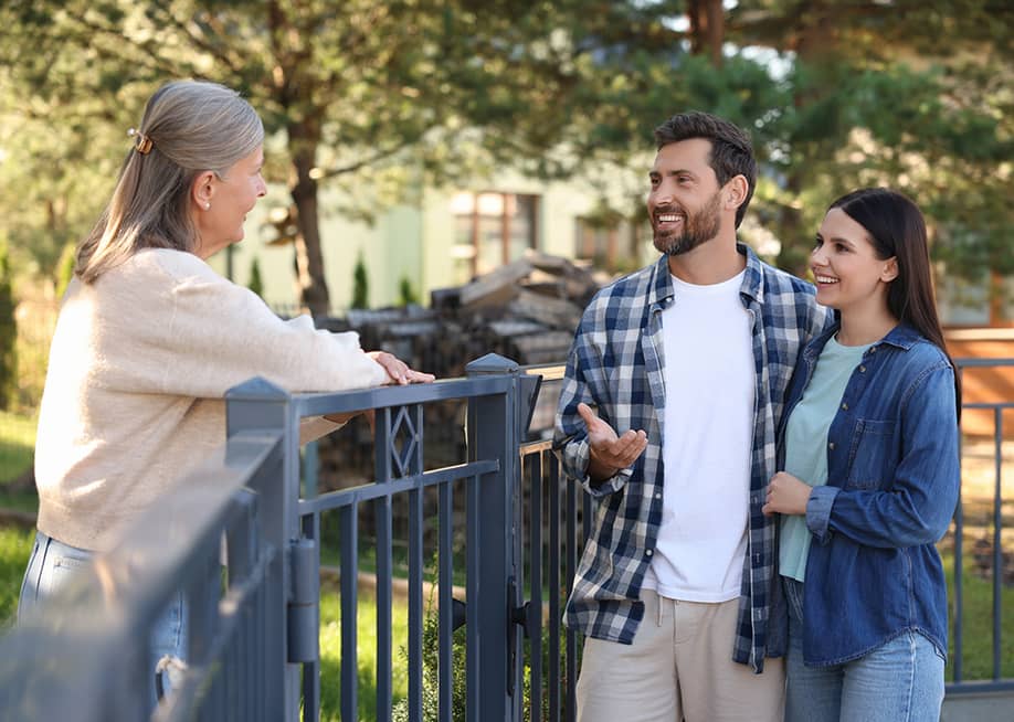 A young couple talking to a friendly elderly neighbor. — New Africa // Shutterstock