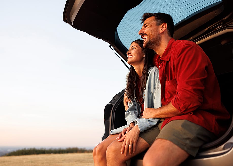 A couple taking a break at their car's trunk from a long drive trip. — Impact Photography // Shutterstock