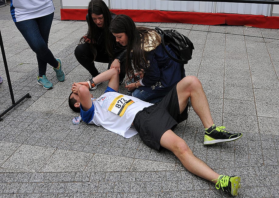 A half-marathon runner collapsing on the ground after crossing the finish line. — vicspacewalker // Shutterstock