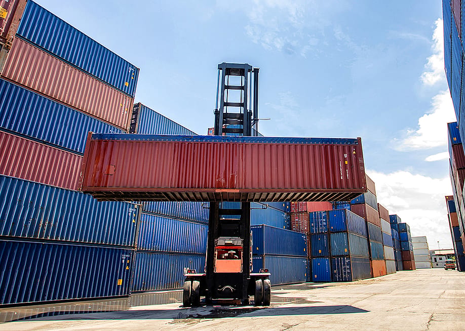 A cargo container being lifted in a shipping yard. — I AM NIKOM // Shutterstock
