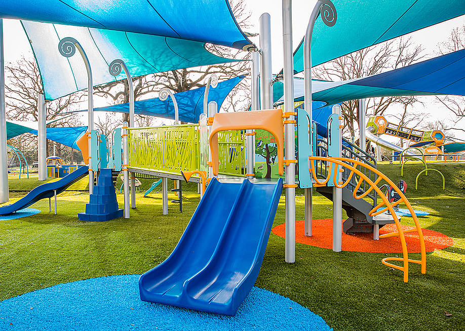 A colorful, modern playground with slides, bridge, climbing stairs, and a canopy. — Charise Wilson // Shutterstock