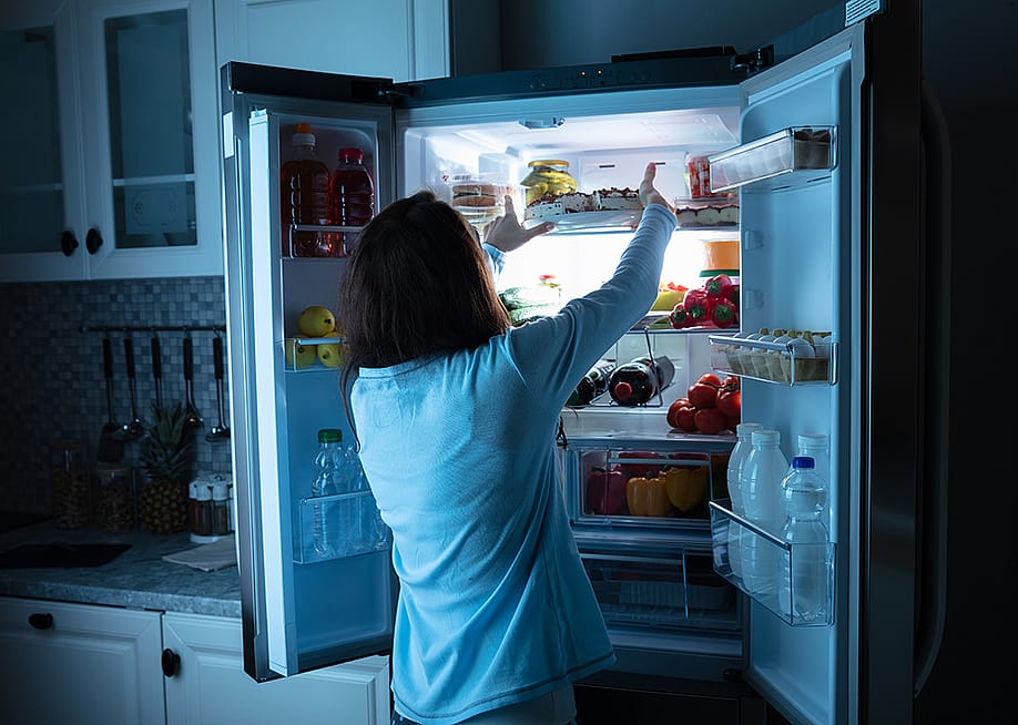 Woman storing food in the refrigerator at night. — Andrey_Popov // Shutterstock