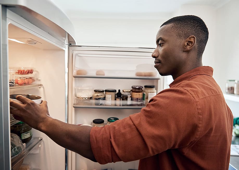 A person checking food items inside a refrigerator from the kitchen. — mavo // Shutterstock