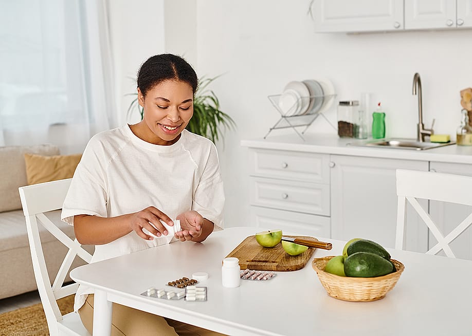 A nutritionist taking food supplements alongside eating fresh fruits at home. — LightField Studios // Shutterstock