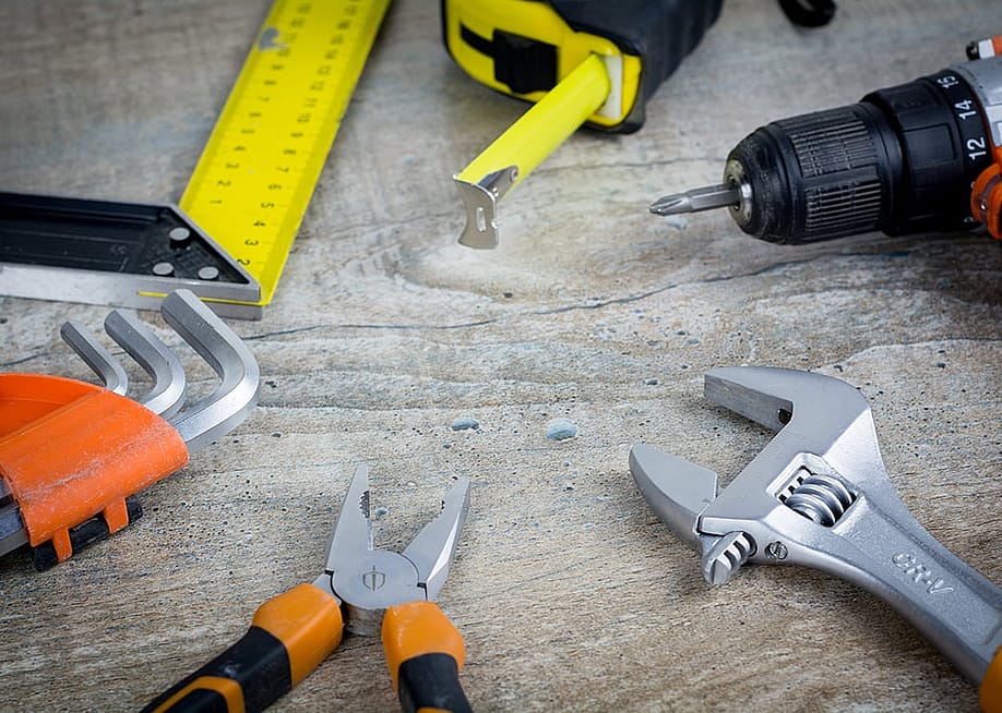 Assorted construction hand tools scattered on a work surface. — BERMIX STUDIO // Shutterstock