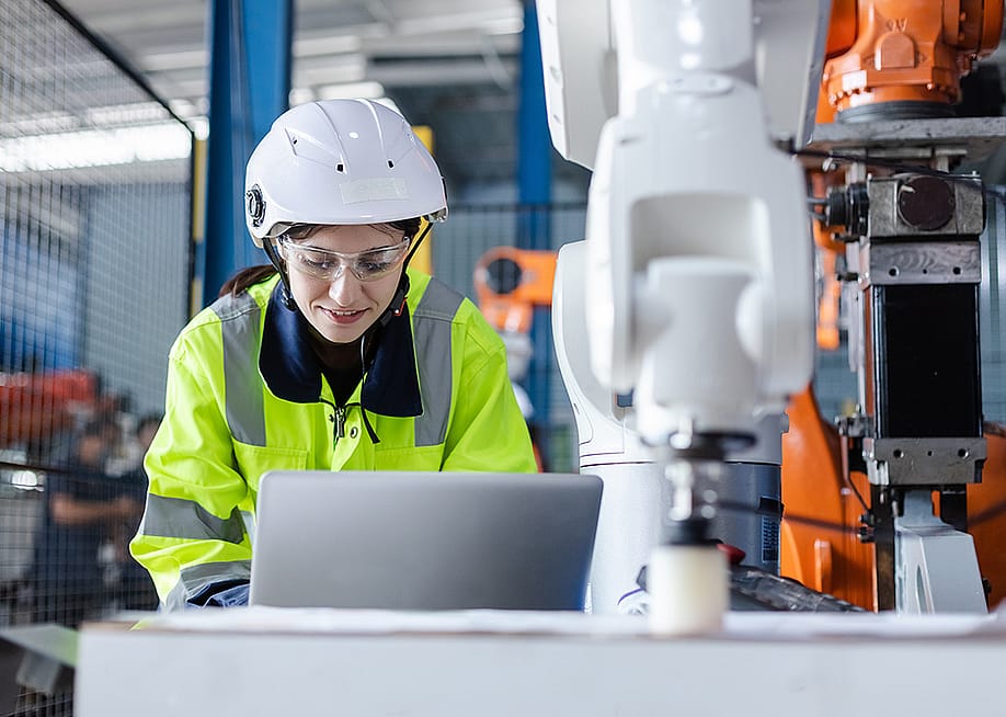 An engineer checking automation robotics from a laptop for a manufacturing machine in an industrial factory. — FOTO Eak // Shutterstock