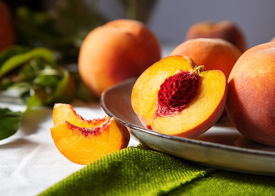 A freshly cut yellow peach with a red pit. — beton studio // Shutterstock