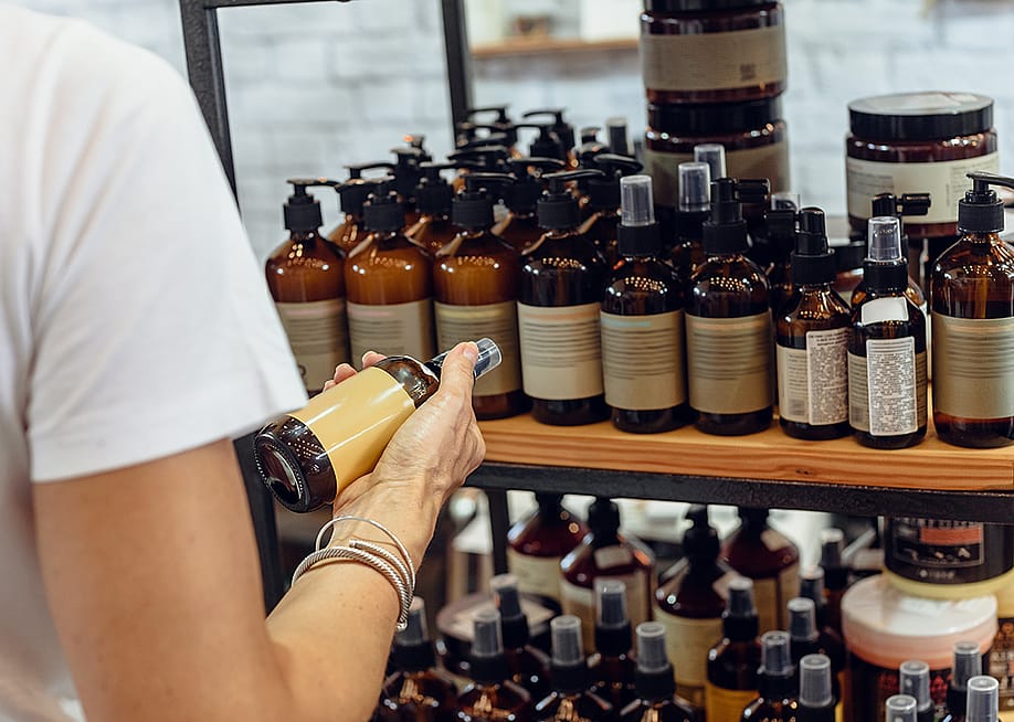 A customer choosing an item among organic cosmetic bottled products. — Denys Kurbatov // Shutterstock
