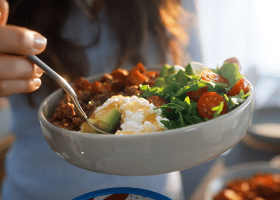 A woman holding a bowl of salad with cottage cheese. — Courtesy of Daisy Brand