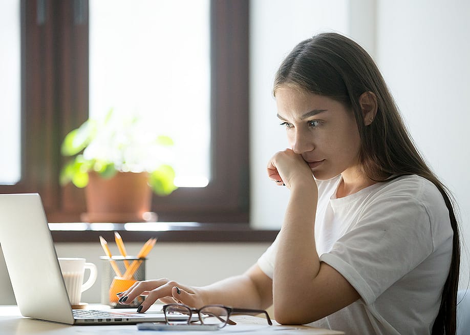 A person appearing to be suspicious while reading from a misleading online content from a laptop. — fizkes // Shutterstock